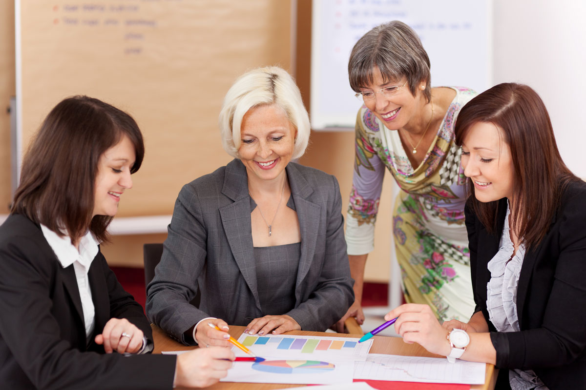 A group of business women of varied ages looking over a financial document