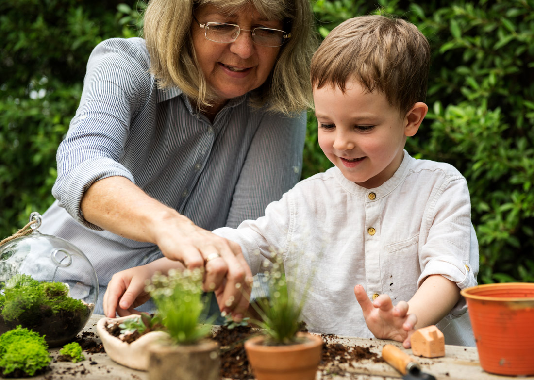 Grandmother and young boy potting plants outdoors